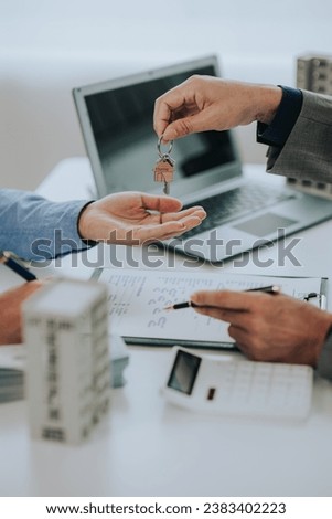 Close-up photo of a real estate agent offering a contract to purchase or rent a residence. Businessman holds small house model with property insurance at table in home sales office Royalty-Free Stock Photo #2383402223