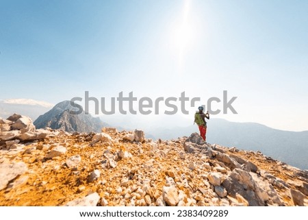 hiking in the mountains. a girl with a backpack takes pictures of the mountains and the sky on the phone from the top of the mountain. climbing and hiking in the mountains.