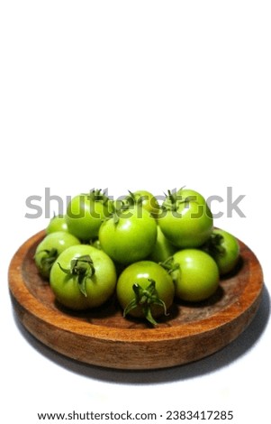 green tomatoes in a wooden plate,isolated on a white background
