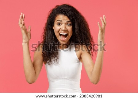 Young stressed furious nervous irritated angry woman of African American ethnicity she wear casual white tank shirt spreading hands scream shout isolated on pink background. People lifestyle concept Royalty-Free Stock Photo #2383420981