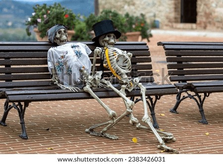 Scary skeletons sit on a bench, an outdoor Halloween decoration, in the Italian town of Solomeo