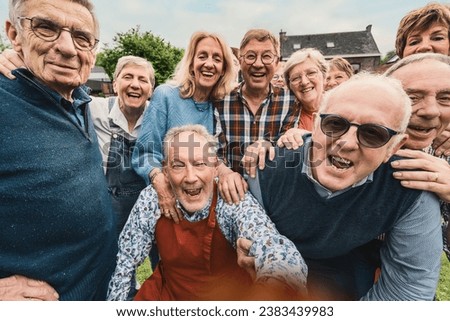 A lively group of senior citizens are caught in a candid moment of pure joy and laughter. Gathered outdoors, their genuine smiles and tight-knit bond radiate warmth and beauty of lifelong friendship. Royalty-Free Stock Photo #2383439983