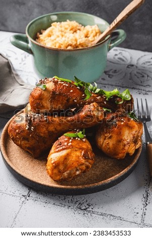 Chicken drumsticks with sesame seeds and rice, Asian cooked chicken on the table vertical photo. High quality photo Royalty-Free Stock Photo #2383453533