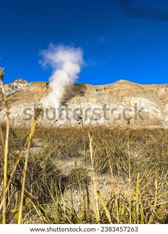 bursts of white smoke from inside the volcanic crater
