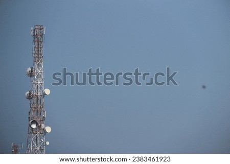 Telecommunication antenna towers are located around rice fields with blue skies