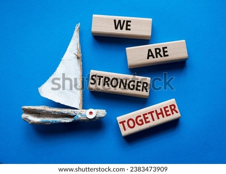 We are stronger together symbol. Wooden blocks with words We are stronger together. Beautiful blue background with boat. We are stronger together concept. Copy space.