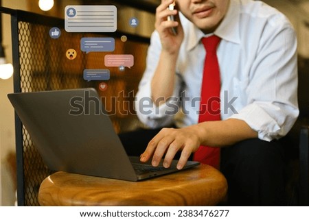 Young businessman having phone conversation and using laptop at coffee shop.