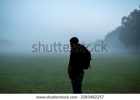 A silhouette of a man looking into the fog