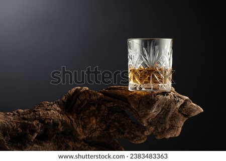 Glass of whiskey on a old wooden snag. Copy space.
