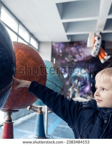 Child holding hand on globe. A child hand on a large model of the planet earth. The concept of protecting the environment, caring for nature and believing in a bright future. Globe and children