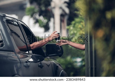 Hand Man in car receiving coffee in drive thru fast food restaurant. Staff serving takeaway order for driver in delivery window. Drive through and takeaway for buy fast food for protect covid19. Royalty-Free Stock Photo #2383489843