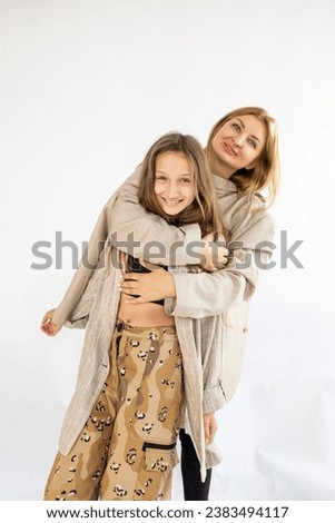 A woman mother in beige suit is having fun with a cute teen girl. Mother, little daughter isolated on white background, studio portrait, Mother's Day, love, family, parenthood, childhood.