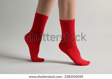Woman in stylish red socks on light grey background, closeup