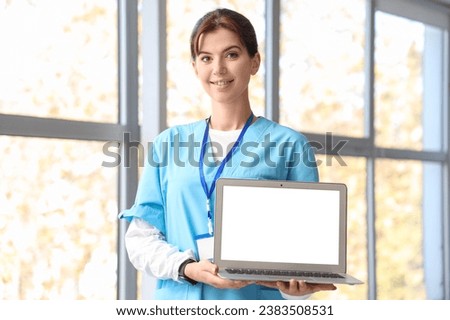 Female medical intern with laptop in hall