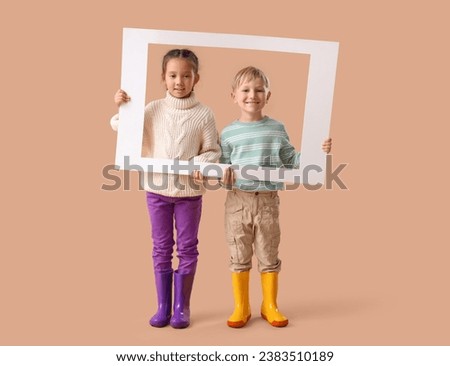 Little children in rubber boots with frame on beige background