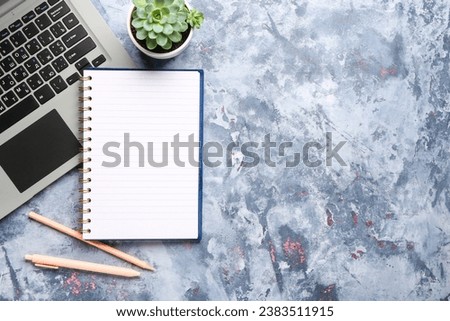 Notebook with pens and laptop on blue background