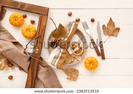 Autumn table setting with pumpkins, chestnuts and dried leaves on white wooden background