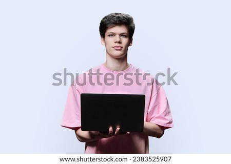 Young male college student using laptop, white background