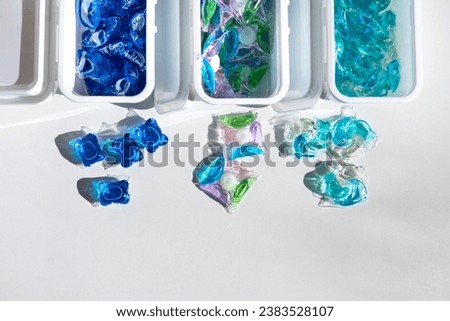 Washing gel capsule pods with laundry detergent on a pile of white cloth background, Capsule with laundry detergent on white background. Home washing concept.