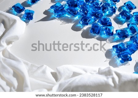 Washing gel capsule pods with laundry detergent on a pile of white cloth background, Capsule with laundry detergent on white background. Home washing concept.