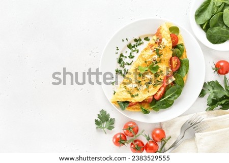 Stuffed omelette with tomatoes and spinach on light stone background with copy space. Top view, flat lay Royalty-Free Stock Photo #2383529555