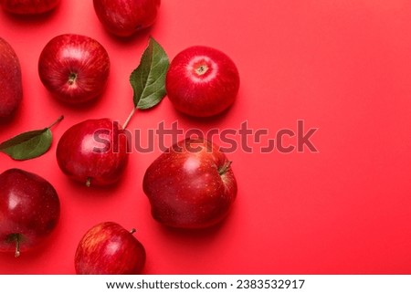 Ripe red apples and green leaves on color background, flat lay. Space for text
