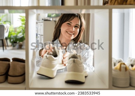 Woman arrangement sneakers on shoes closet shelf comfortable storage organizing method at home. Female footwear cupboard organize neatly folded boots seasonal wardrobe cleaning and maintaining Royalty-Free Stock Photo #2383533945