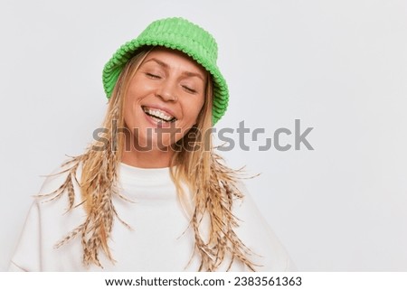 Portrait of happy blonde girl in green hat and white sweatshirt isolated over white background, nice day concept, copy space
