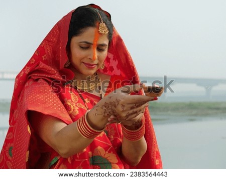 Indian woman holding an earthen lamp in her hand - faith of God, red saree, offering prayers to sun. Hindu woman with handmade clay lamp - Chhath Puja, Bihari festival, Hindu festival, newly wed woman Royalty-Free Stock Photo #2383564443