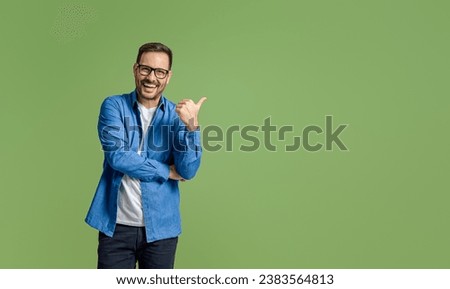 Cheerful young businessman aiming at copy space for marketing while standing on green background