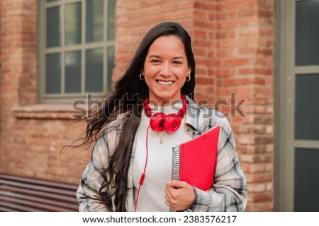 Close up individual portrait of a pretty hispanic female student smiling and looking at camera at high school. Head shot of latin teenage girl standing outdoors at the university campus. Education