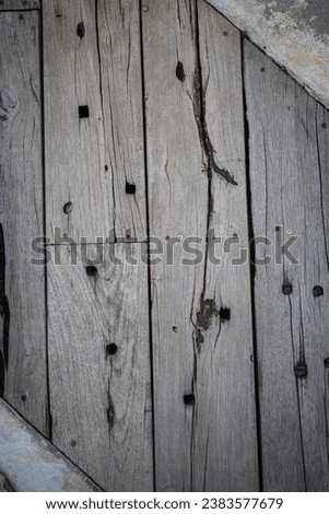The picture shows gray wooden panels that have been hammered with many holes and grooves used to decorate the walls
