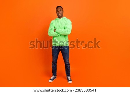 Full size photo of confident positive cheerful man wear stylish sportswear jeans standing hands crossed isolated on orange background