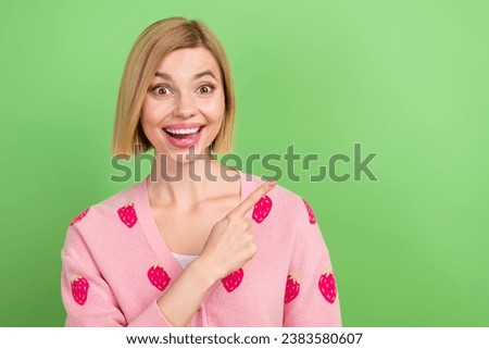 Photo of young funky girl blonde bob hair wear pink strawberry shirt pointing empty space presentation isolated on green color background