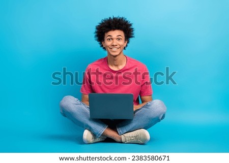 Full body photo of handsome young male sit floor folded legs working laptop dressed stylish pink outfit isolated on blue color background