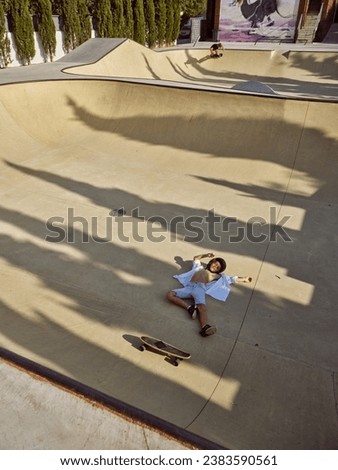 From above full length of kid fallen from longboard in skate park in sunny day