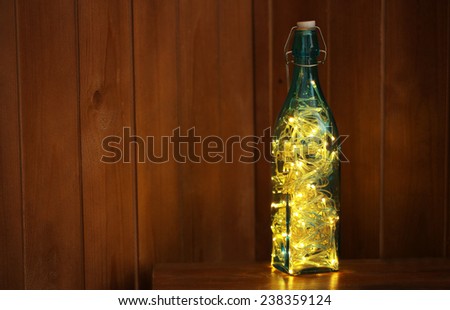 Christmas lights in bottle on wooden background