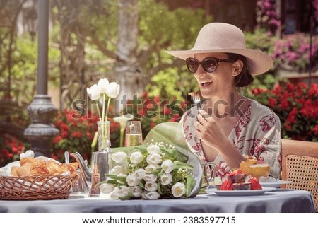 Stock photo of happy woman eating fruit in the garden during sunny day.