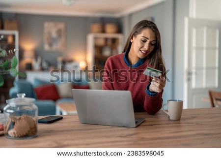 Happy female freelancer adding credit card details in laptop while shopping online from home.