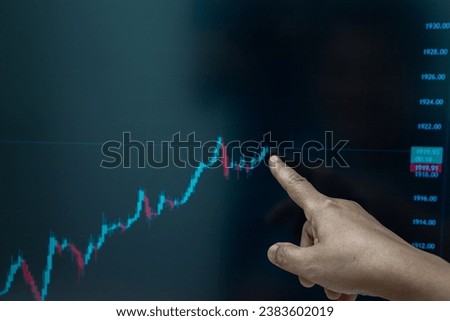 Hand of elderly woman points at the green bar chart of an investment or stock market on a computer screen. Royalty-Free Stock Photo #2383602019