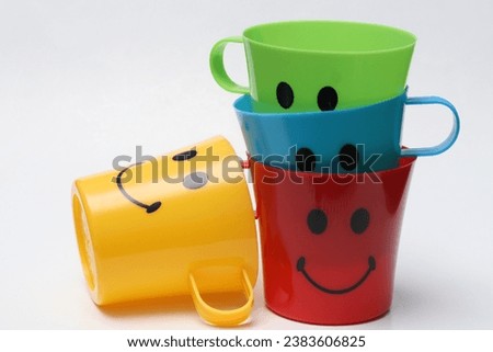 
Some plastic cups are yellow, blue, green and red. There is a picture of a smile pattern on the side.Isolated white.The concept of happiness and hospitality.