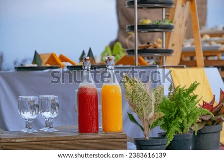 Food was on picnic tables set with red and yellow drink in bottle - Picnic set