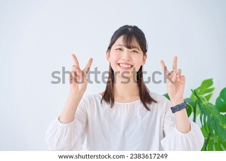 young woman doing peace sign                            Royalty-Free Stock Photo #2383617249
