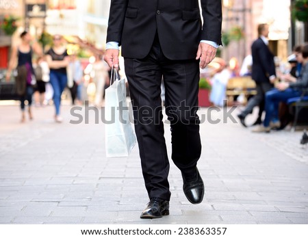 Man in suit with shopping bag on sunny shopping street