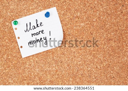 Paper sheet with inscription "Make more money" on wooden background