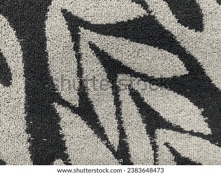 
close up photo from above of a black ang grey doormat with a floral pattern