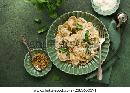 Homemade Italian ravioli pasta in heart shape with beef meat, cheese sauce, caramelized onions, basil and saffron on old green background. Food cooking menu ingredients background. Top view.