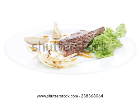 meat food : grilled steak on green lettuce salad , with roast onion, on dish isolated over white background