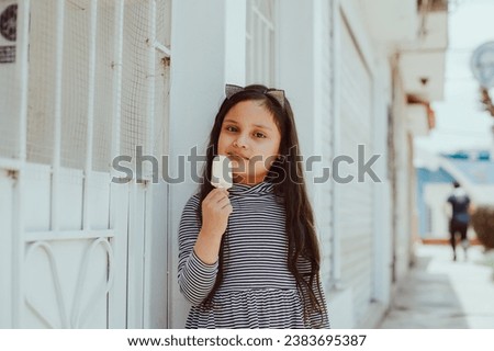 Picture of adorable happy girl eating an ice-cream outdoors. Concept of people, children and lifestyle.