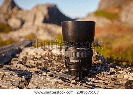 Macro lens from camera on the background of grass and stones in the tundra. Modern photographic equipment in the bright sunset light at the outdoor